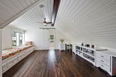 an attic bedroom with white walls and wood flooring, built in shelving units