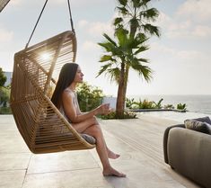 a woman sitting in a hanging chair next to a pool