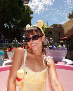 a woman wearing sunglasses and holding a stuffed animal in front of a pink water slide