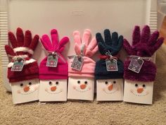 five small snowman mittens are lined up in front of a white box on the floor