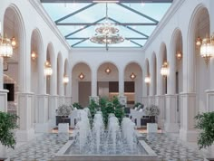 an indoor fountain in the middle of a lobby with chandeliers and potted plants