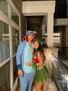 a man and woman dressed in costumes standing next to each other on a porch at night