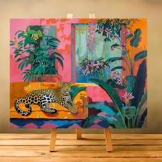 a painting is displayed on an easel in front of a wall with plants and flowers