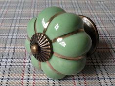 a close up of a green door knob on a checkered table cloth with gold accents