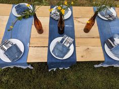 the table is laid out with plates and vases on it, along with jeans napkins