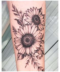 a sunflower tattoo on the leg with black and white flowers in front of it