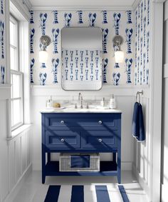 a bathroom with blue and white decor on the walls, sink, mirror and rug