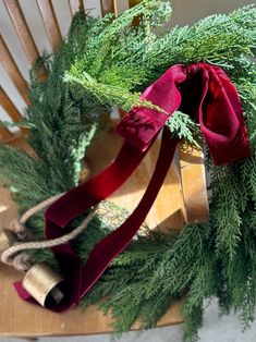 a wooden rocking chair decorated with christmas greenery and red ribbon tied around the top