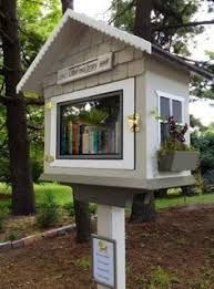 a small white house sitting in the middle of a tree filled park with lots of books