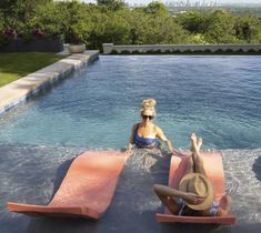 two people sitting on inflatable mattresses at the edge of a swimming pool