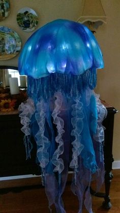 a large blue jellyfish sitting on top of a wooden floor next to a table