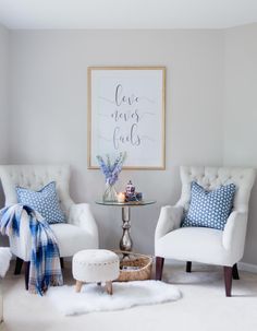 a living room with two white chairs and a glass top table in front of it