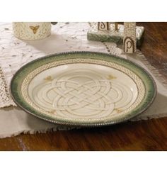 a white and green plate sitting on top of a wooden table next to a vase