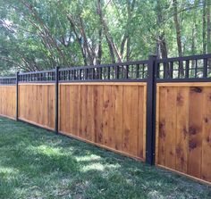 a wooden fence with metal railings in the grass