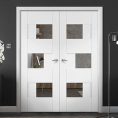 two white doors in a room with black walls and wood flooring on the side