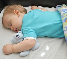 a baby is sleeping on a bed with a stuffed animal