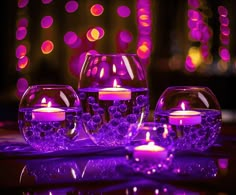 purple candles are lit in glass vases on a table