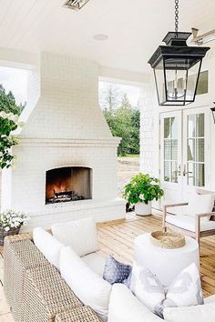 a porch with white furniture and a fireplace