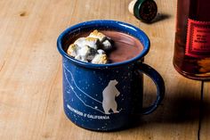 a cup filled with hot chocolate and marshmallows on top of a wooden table