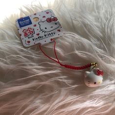 a hello kitty keychain with a red ribbon around it's neck and a white cat head