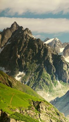 the mountains are covered in snow and green grass