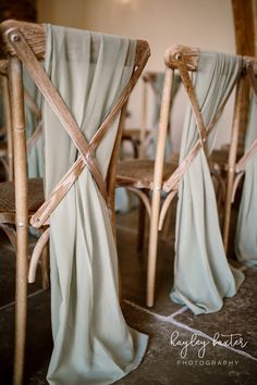 two wooden chairs with drapes draped over them