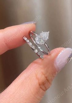 a woman's hand holding an engagement ring with two diamonds on the top and bottom