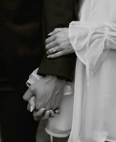 the bride and groom hold hands as they stand close to each other in black and white