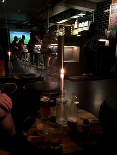 people are sitting at a bar with candles in front of them