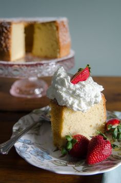 a piece of cake with whipped cream and strawberries on the plate next to it