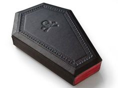 a black leather book with a skull and cross on the cover is sitting on a white surface