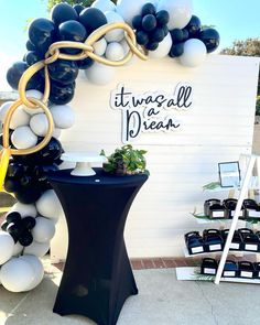 there is a balloon arch that has been decorated with black, white and gold balloons