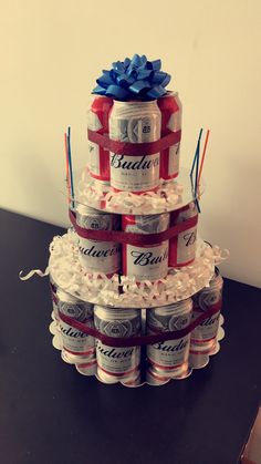 a tiered cake made out of cans and wrapped in ribbon, sits on a table