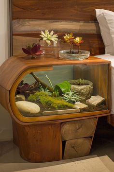 a bed with a wooden headboard and side table filled with rocks, plants and moss