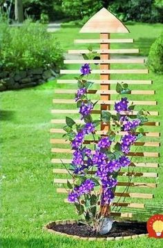 purple flowers are growing in the middle of a flower pot with a wooden structure behind it