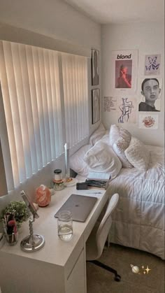 a bedroom with white bedding and pictures on the wall above it, along with a laptop computer