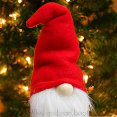 a red and white gnome hat sitting on top of a wooden table next to a christmas tree