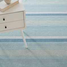 a white table with a book on top of it next to a blue striped rug