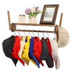 there is a rack with hats hanging from it's hooks, and a framed picture on the wall