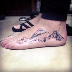 a person with a mountain tattoo on their foot