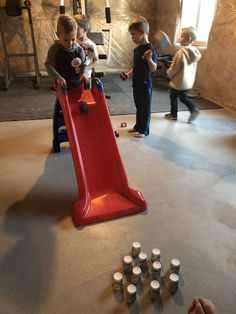 two children playing on a slide in the middle of a room with cups and bottles