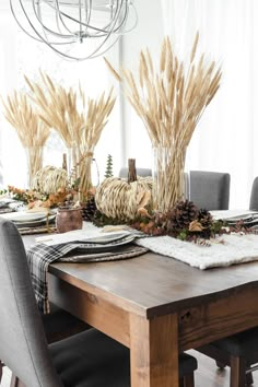 a dining room table set with place settings and fall decorations on the top of it