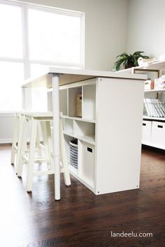 a kitchen island with two stools in front of it and an open shelf on the other side