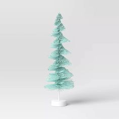 a small green christmas tree sitting on top of a white base