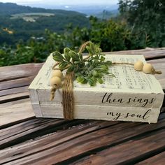 an open book with a plant growing out of it sitting on top of a wooden table