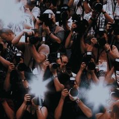 a large group of people with cameras taking pictures