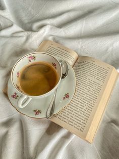 a cup of coffee sitting on top of a saucer next to an open book