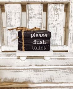 a wooden sign that says please flush toilet on the side of a white painted bench