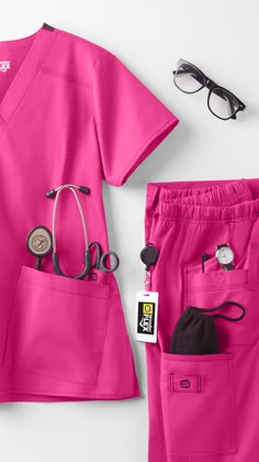 pink medical scrubs and eyeglasses laid out on a white surface