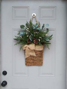 a basket with flowers hanging on the front door